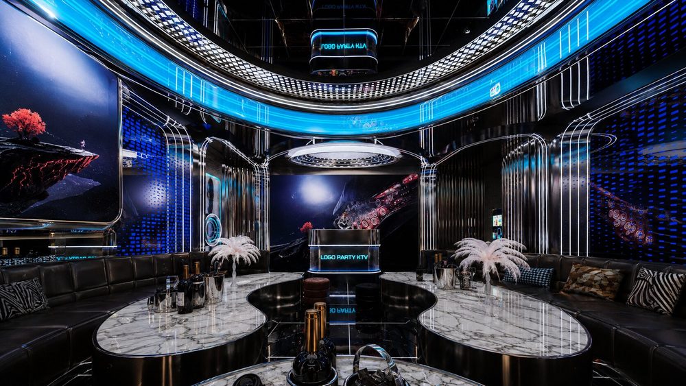 Thiết kế phòng KTV Futuristic Luxury gây ấn tượng bởi sự kết hợp giữa kiến trúc hình học, ánh sáng LED và vật liệu cao cấp. Trần cong nhiều lớp, vách kim loại phản sáng, màn hình nghệ thuật và hệ sofa đen tạo nên không gian vừa hiện đại vừa sang trọng. 